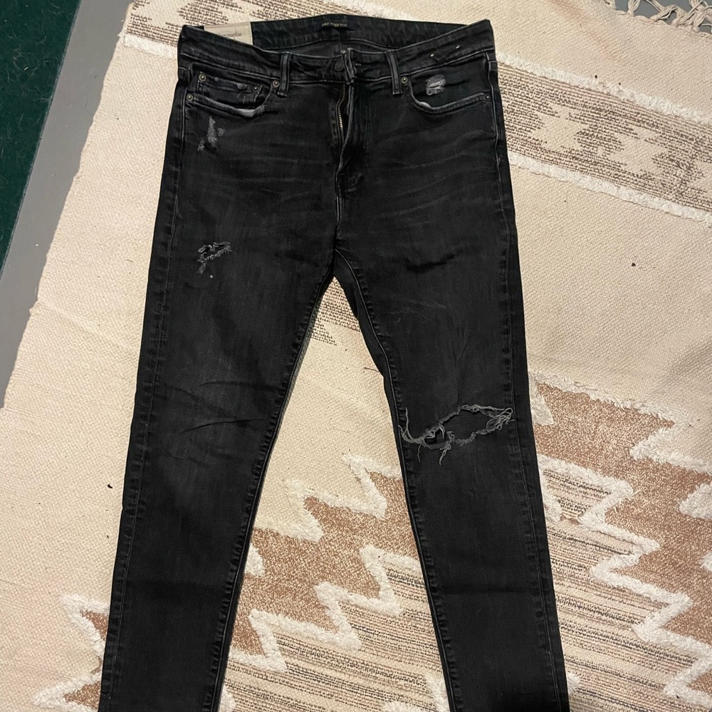 Men’s lightly worn and lightly faded black slim distressed Abercrombie denim.